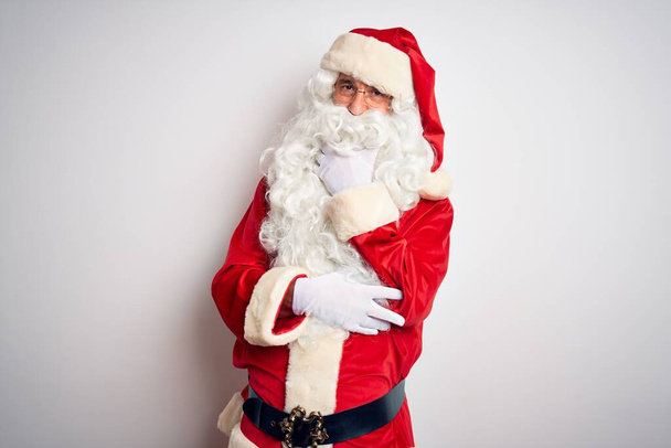 Medioevo bell'uomo che indossa il costume di Babbo Natale in piedi su sfondo bianco isolato guardando fiducioso la fotocamera sorridente con le braccia incrociate e la mano sollevata sul mento. Pensare positivo
. - Foto, immagini