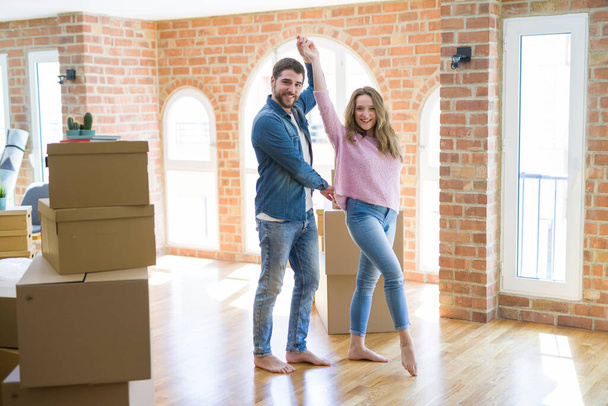 Pareja joven bailando celebrando mudarse a un nuevo apartamento alrededor de cajas de cartón
 - Foto, imagen
