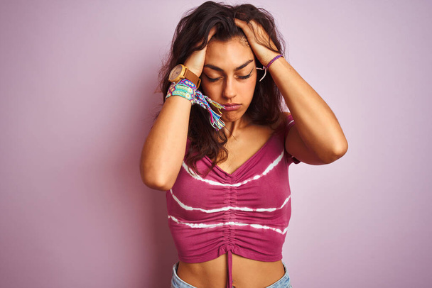 Young beautiful woman wearing casual t-shirt standing over isolated pink background suffering from headache desperate and stressed because pain and migraine. Hands on head. - Foto, afbeelding