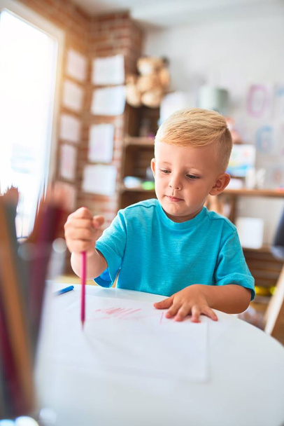 Jeune enfant caucasien jouant à la maternelle dessin avec des crayons de couleur. Garçon d'âge préscolaire heureux à la salle de jeux
. - Photo, image