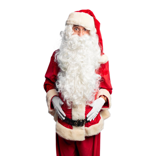 Середній вік вродливий чоловік у костюмі Санта Клауса і бороді стоїть переляканий і шокований здивованим і здивованим виразом, страхом і схвильованим обличчям.. - Фото, зображення
