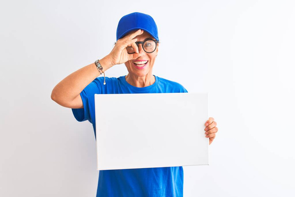 Старший Delywoman в шапочці і окулярах тримає банер над ізольованим білим тлом з щасливим обличчям посміхаючись роблячи знак добре з рукою на око дивиться через пальці
 - Фото, зображення