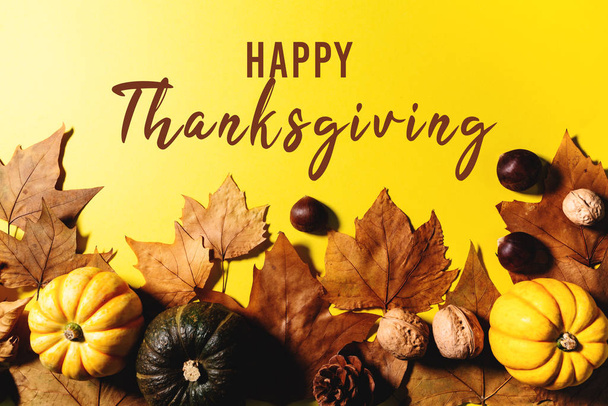Gelukkige Thanksgiving Dag met esdoorn bladeren, noten en pompoen op gele achtergrond - Foto, afbeelding