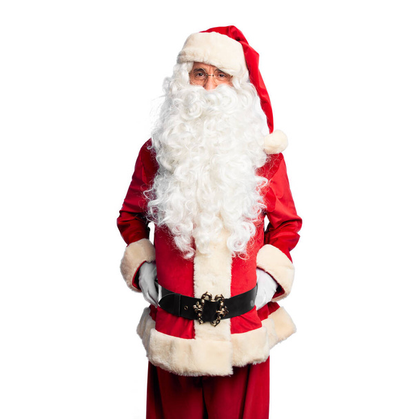 Pohledný muž středního věku v kostýmu Santa Clause a s vousy stojí se šťastným a chladným úsměvem na tváři. Šťastný člověk. - Fotografie, Obrázek