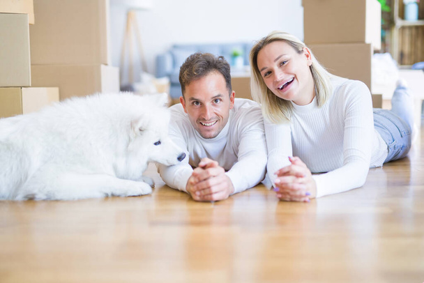 Jeune beau couple avec chien couché sur le sol à la nouvelle maison autour des boîtes en carton
 - Photo, image
