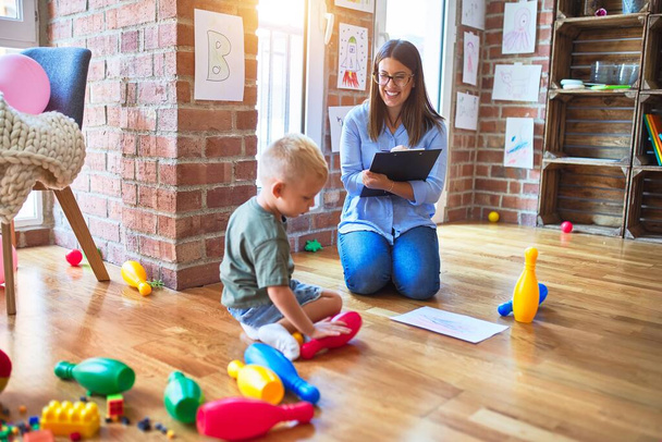 Mujer terapeuta joven que habla con el niño, consejero y corrección de comportamiento en la oficina alrededor de los juguetes
 - Foto, Imagen