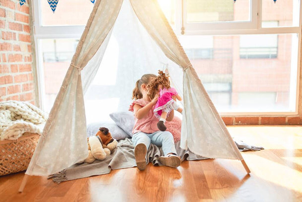 Beautiful blond toddler girl playing with dolls inside tipi at kindergarten - 写真・画像