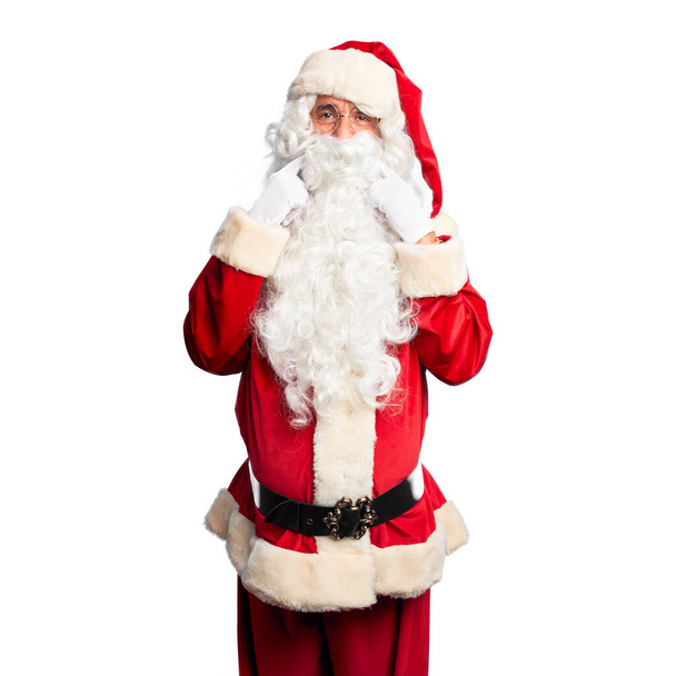 Middelbare leeftijd knappe man draagt Kerstman kostuum en baard staande glimlachen met open mond, vingers wijzen en dwingen vrolijke glimlach - Foto, afbeelding