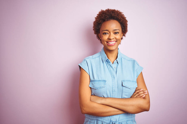 Jeune belle femme afro-américaine aux cheveux afro sur fond rose isolé heureux visage souriant avec les bras croisés en regardant la caméra. Personne positive
. - Photo, image