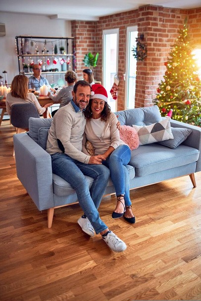 Rodzina i przyjaciele jadalnia w domu świętując Wigilię Bożego Narodzenia z tradycyjnym jedzeniem i dekoracji, romantyczna para seniorów rozmawiając razem siedzi na kanapie - Zdjęcie, obraz