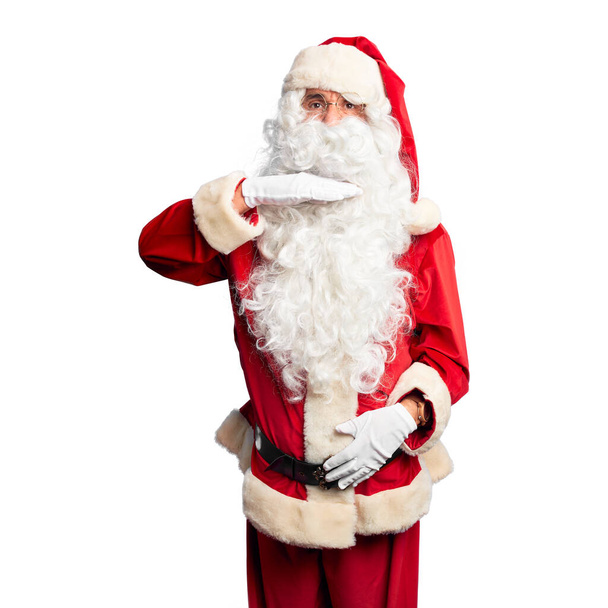 Homem bonito de meia idade vestindo traje de Papai Noel e barba de pé cortando garganta com a mão como faca, ameaçar a agressão com violência furiosa
 - Foto, Imagem