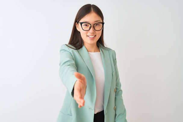 Chinesische Geschäftsfrau in eleganter Jacke und Brille über isoliertem weißem Hintergrund, freundlich lächelnd und per Handschlag zur Begrüßung. Erfolgreiches Geschäft. - Foto, Bild