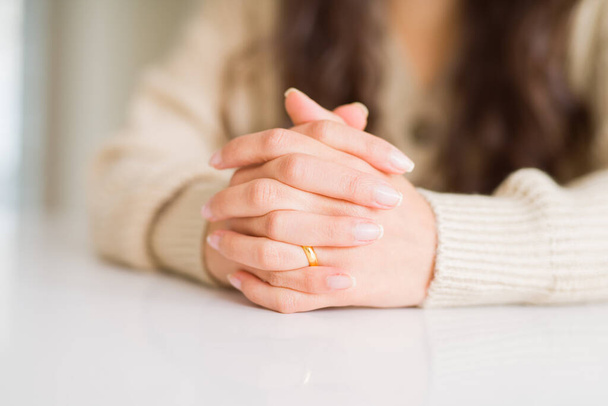 Nahaufnahme einer Frau mit gekreuzten Händen, die eine goldene Allianz für die Ehe trägt - Foto, Bild