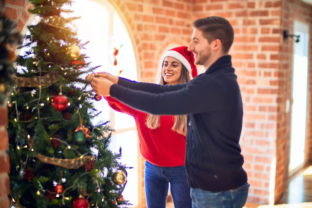 Young beautiful couple smiling happy and confident around christmas tree at home - Photo, Image