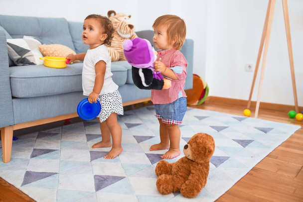 Adorable toddlers playing with teddy bear around lots of toys at kindergarten - Fotoğraf, Görsel