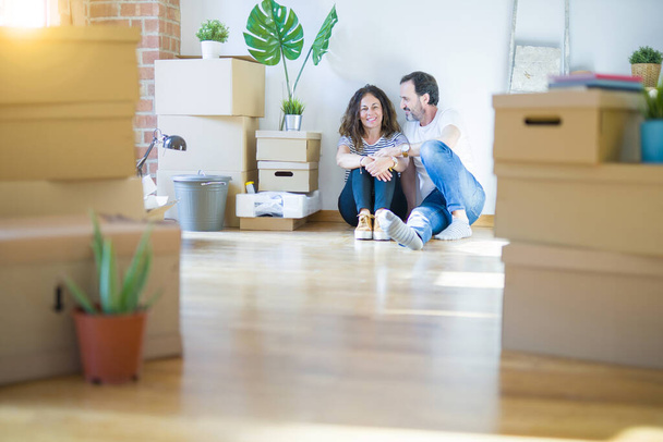 Couple romantique sénior d'âge moyen amoureux assis sur le sol de l'appartement avec des boîtes en carton autour et souriant heureux de déménager dans une nouvelle maison
 - Photo, image