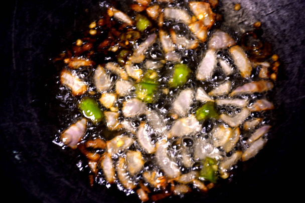Sütő hagyma, fokhagyma és chili pisa forró olajban, vasserpenyőben. - Fotó, kép