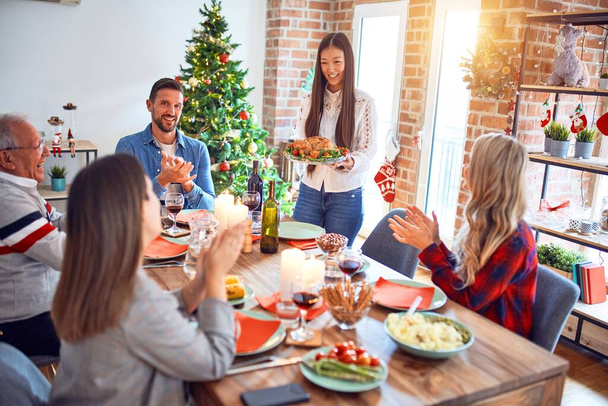 Belle réunion de famille souriant heureux et confiant. Personne debout tenant la dinde rôtie célébrant Noël à la maison
 - Photo, image