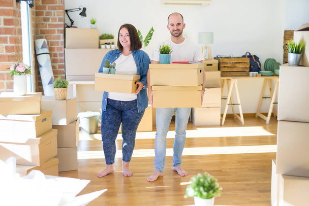 junges Paar zieht in ein neues Zuhause und lächelt glücklich in Kartons - Foto, Bild