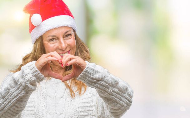 Középkorú vezető spanyol nő visel kalapot karácsonyi felett mosolygó szerelmes szív szimbólum és a kéz alakú elszigetelt háttér. Romantikus fogalma. - Fotó, kép