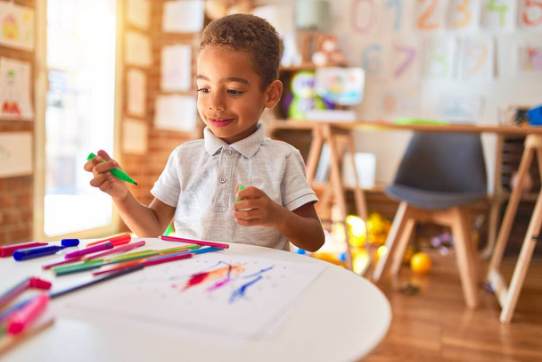 Desenho de criança americana africana bonita usando papel e caneta marcador sorrindo no jardim de infância
 - Foto, Imagem