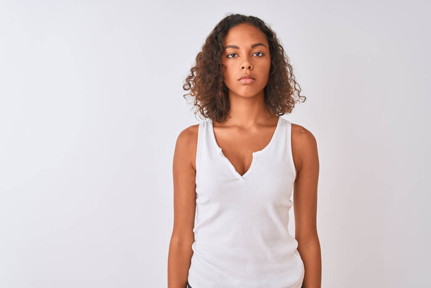 Jeune femme brésilienne portant un t-shirt décontracté debout sur fond blanc isolé Relaxé avec une expression sérieuse sur le visage. Un regard simple et naturel sur la caméra
. - Photo, image
