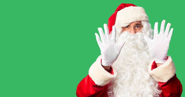 Pohledný muž středního věku v kostýmu Santa Clause a vousy stojící a ukazující prstem číslo deset a usmívající se sebevědomě a šťastně. - Fotografie, Obrázek