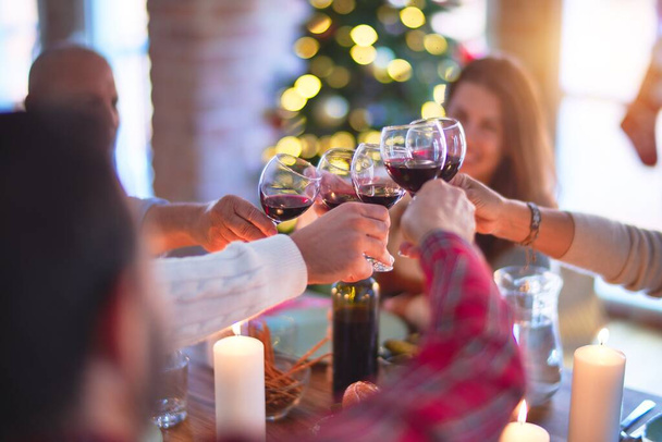 Gyönyörű család mosolyogva boldog és magabiztos. Pörkölt pulykát enni és pohárköszöntőt mondani egy pohár borral ünnepelni a karácsonyt otthon. - Fotó, kép