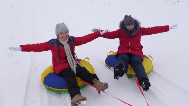 Happy children sledding in snow in the winter and waving their hands. family plays in winter park during the Christmas holidays. children laugh and rejoice. Slow motion. concept of a happy family. - Footage, Video