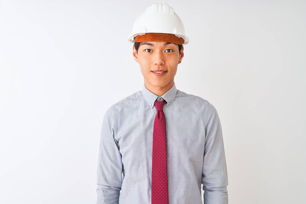 Homem arquiteto chinês usando gravata e capacete em pé sobre fundo branco isolado com um sorriso feliz e legal no rosto. Pessoa com sorte
. - Foto, Imagem