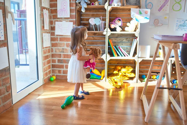 Adorável criança loira brincando em torno de lotes de brinquedos no jardim de infância
 - Foto, Imagem