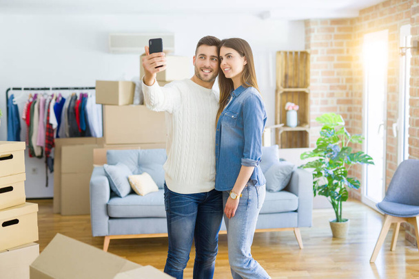 Hermosa pareja tomando una foto selfie usando un teléfono inteligente en un nuevo
 - Foto, imagen