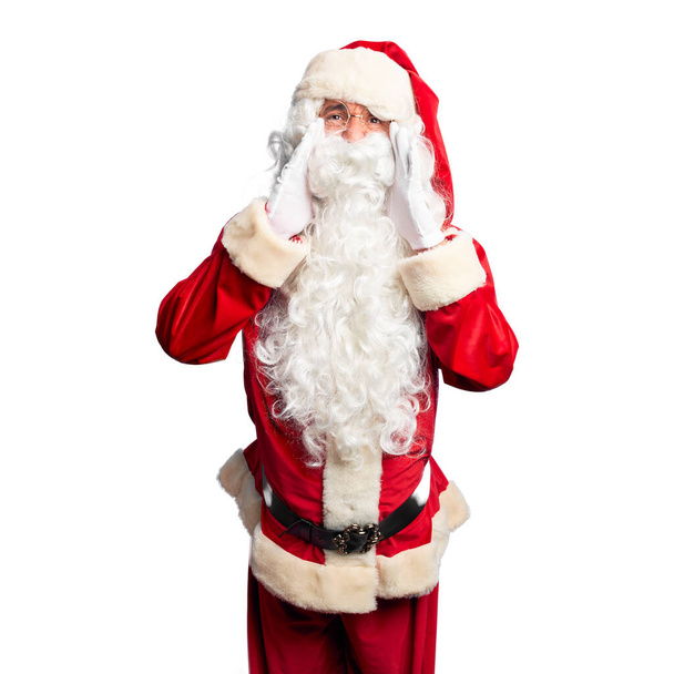 Middelbare leeftijd knappe man draagt Kerstman kostuum en baard staan Schreeuwen boos hardop met handen over de mond - Foto, afbeelding