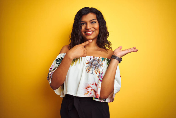 Transsexual transgender woman wearing summer t-shirt over isolated yellow background amazed and smiling to the camera while presenting with hand and pointing with finger. - Photo, Image