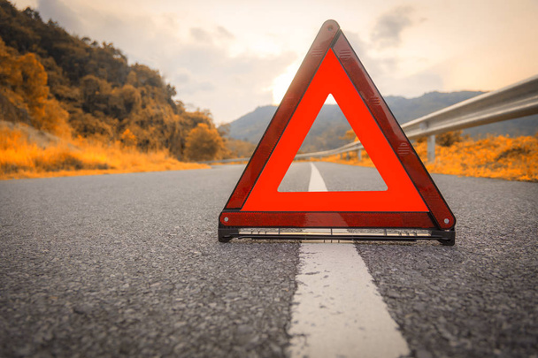 Jesienna droga Czerwony trójkąt, czerwony awaryjny znak stopu, czerwony symbol awaryjny na drodze. Z powierzchnią do kopiowania tekstu lub projektu - Zdjęcie, obraz