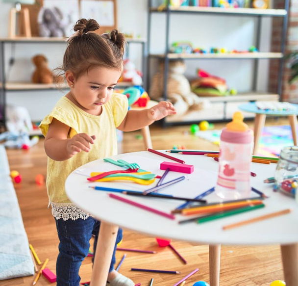 Kaunis lapsi seisoo leikkimässä leluilla pöydällä päiväkodissa
 - Valokuva, kuva