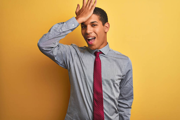 Young handsome arab businessman wearing shirt and tie over isolated yellow background surprised with hand on head for mistake, remember error. Forgot, bad memory concept. - Foto, Imagem