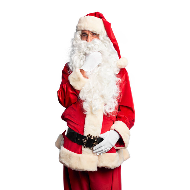 Middelbare leeftijd knappe man draagt Santa Claus kostuum en baard staan kijken zelfverzekerd naar de camera glimlachend met gekruiste armen en hand geheven op kin. Positief denken. - Foto, afbeelding
