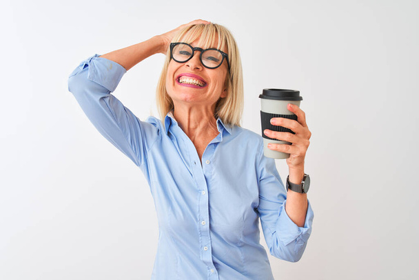 Middle age businesswoman wearing glasses drinking coffee over isolated white background stressed with hand on head, shocked with shame and surprise face, angry and frustrated. Fear and upset for mistake. - Fotografie, Obrázek