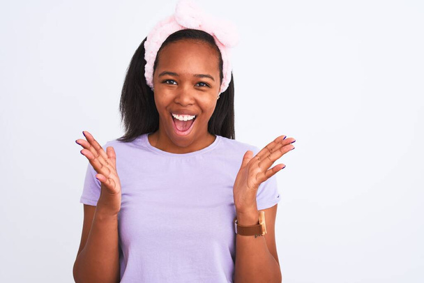 Beautiful young african american woman wearing a beauty diadem over isolated background very happy and excited, winner expression celebrating victory screaming with big smile and raised hands - Photo, Image
