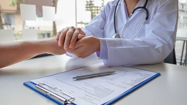 女性医師は、患者の手を握って自信を与え、医療についてのケアを示すために友好的な手を使用しています。医療の概念と健康 - 写真・画像