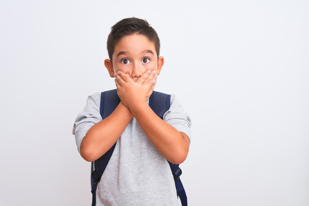 Beautiful student kid boy wearing backpack standing over isolated white background shocked covering mouth with hands for mistake. Secret concept. - Fotografie, Obrázek