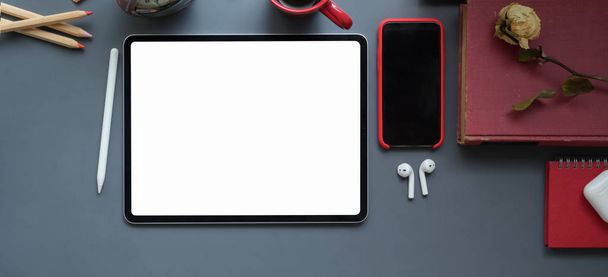 Fejlövés a modern munkahely üres képernyős tabletta, irodai kellékek és okostelefon sötét szürke asztal háttér  - Fotó, kép