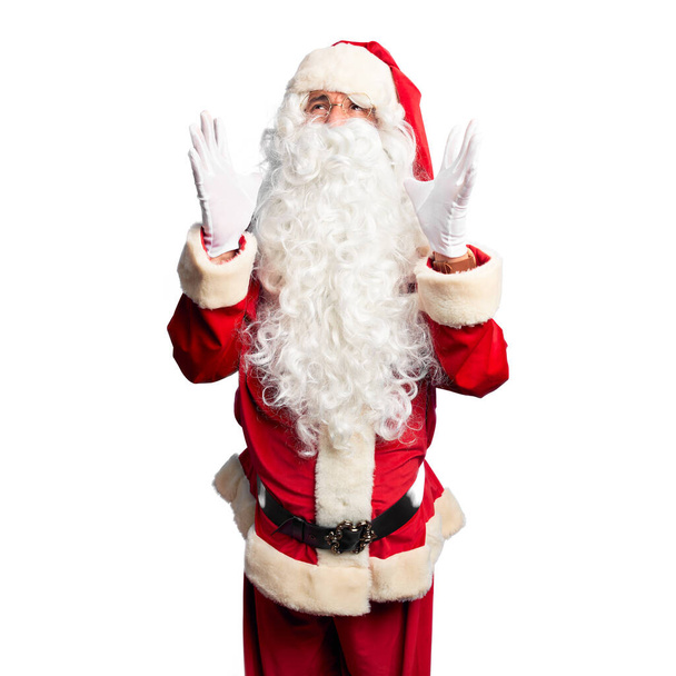 Pohledný muž středního věku, oblečený v kostýmu Santa Clause a s vousy, jak šíleně a šíleně křičí a křičí s agresivním výrazem a zdviženýma rukama. Koncept frustrace. - Fotografie, Obrázek