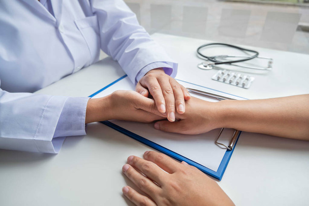 Kadın doktor, hastanın elini tutmak için dost canlısı bir el kullanır. Güvenini kazanmak ve sağlık hizmetlerine önem verdiğini göstermek için. Tıbbi kavramlar ve sağlık - Fotoğraf, Görsel