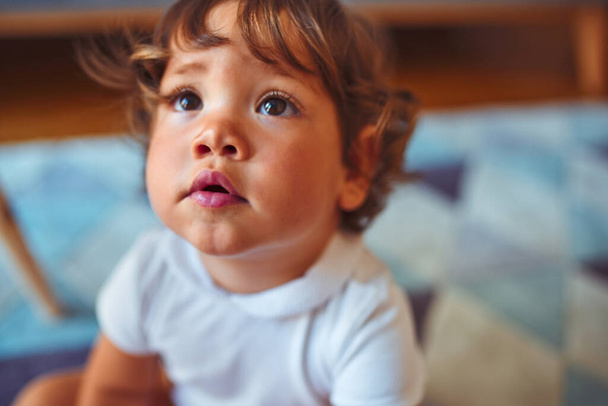 Hermosa niña pequeña con camiseta blanca jugando en la alfombra
 - Foto, Imagen