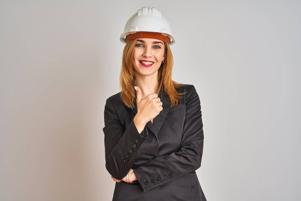 Redhead caucasian business woman wearing safety helmet over isolated background doing happy thumbs up gesture with hand. Approving expression looking at the camera with showing success. - Фото, изображение