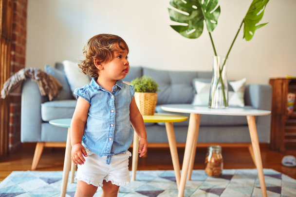 Mooi peuter kind meisje dragen blauwe denim shirt staan op de vloer - Foto, afbeelding