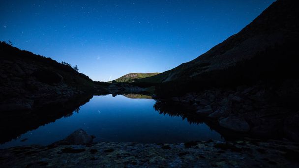 Csillagos éjszakai égbolt tükrözi a kristálytiszta víz Alpesi-tó Alacsony-Tátra Szlovákia - Fotó, kép