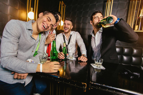 Grupo de amigos masculinos sonrientes divirtiéndose en club nocturno  - Foto, Imagen